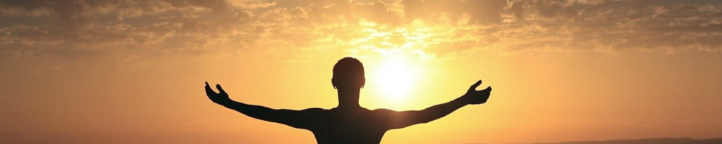 Silhouette of a person, arms open, welcoming the sunrise